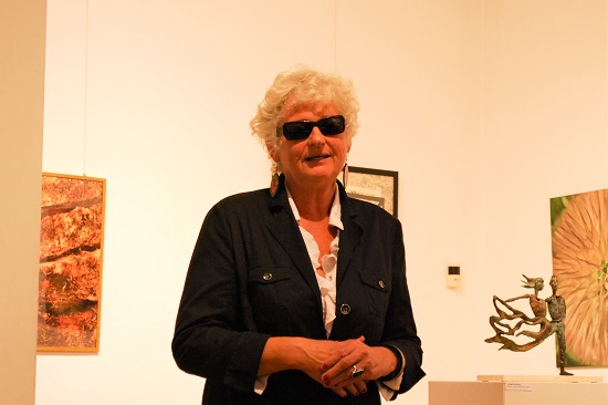 Niewidoma kobieta w ciemnych okularach przemawia w galerii sztuki.